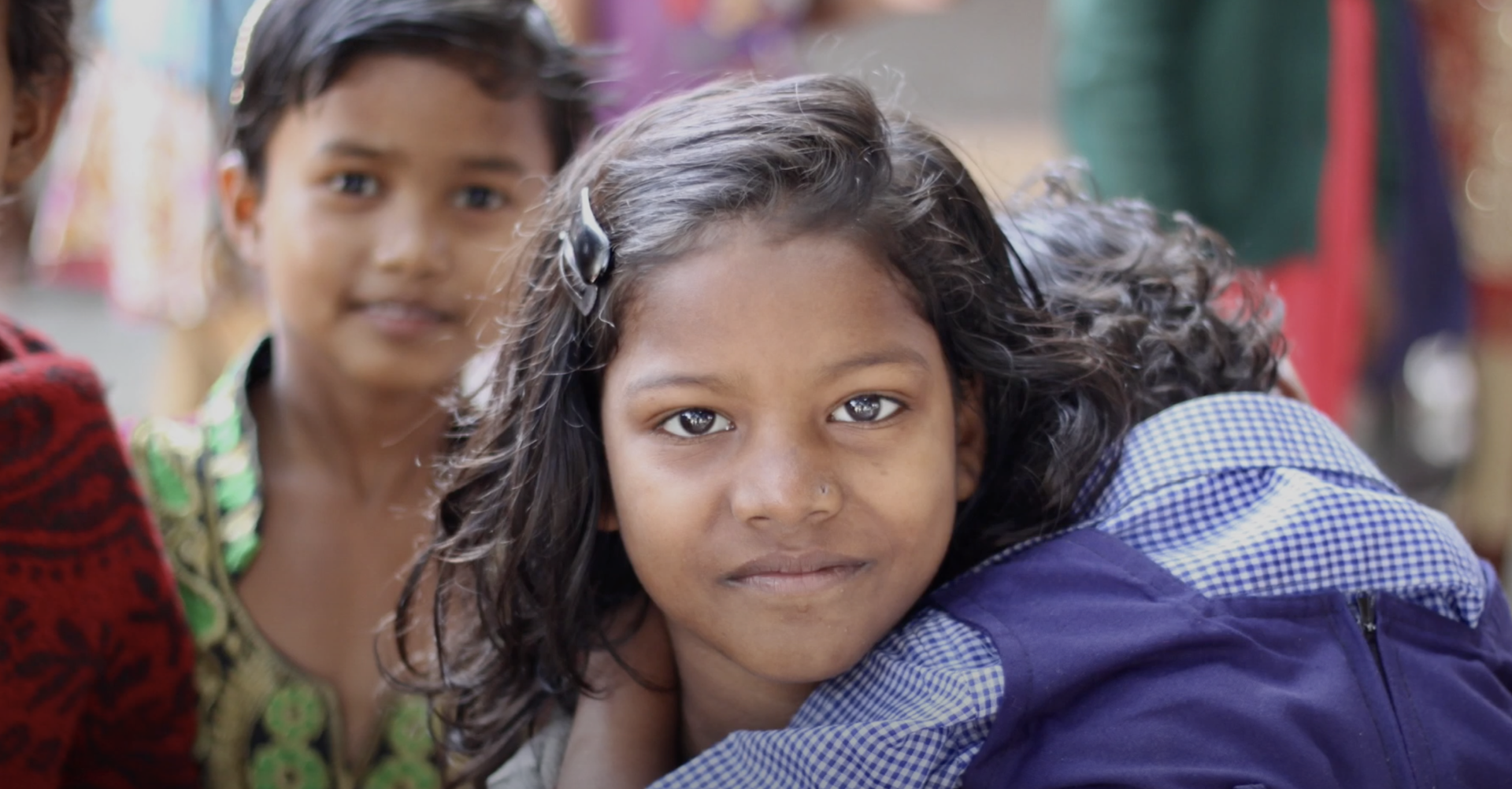 A young Santal girl resting her head on a friend's shoulder