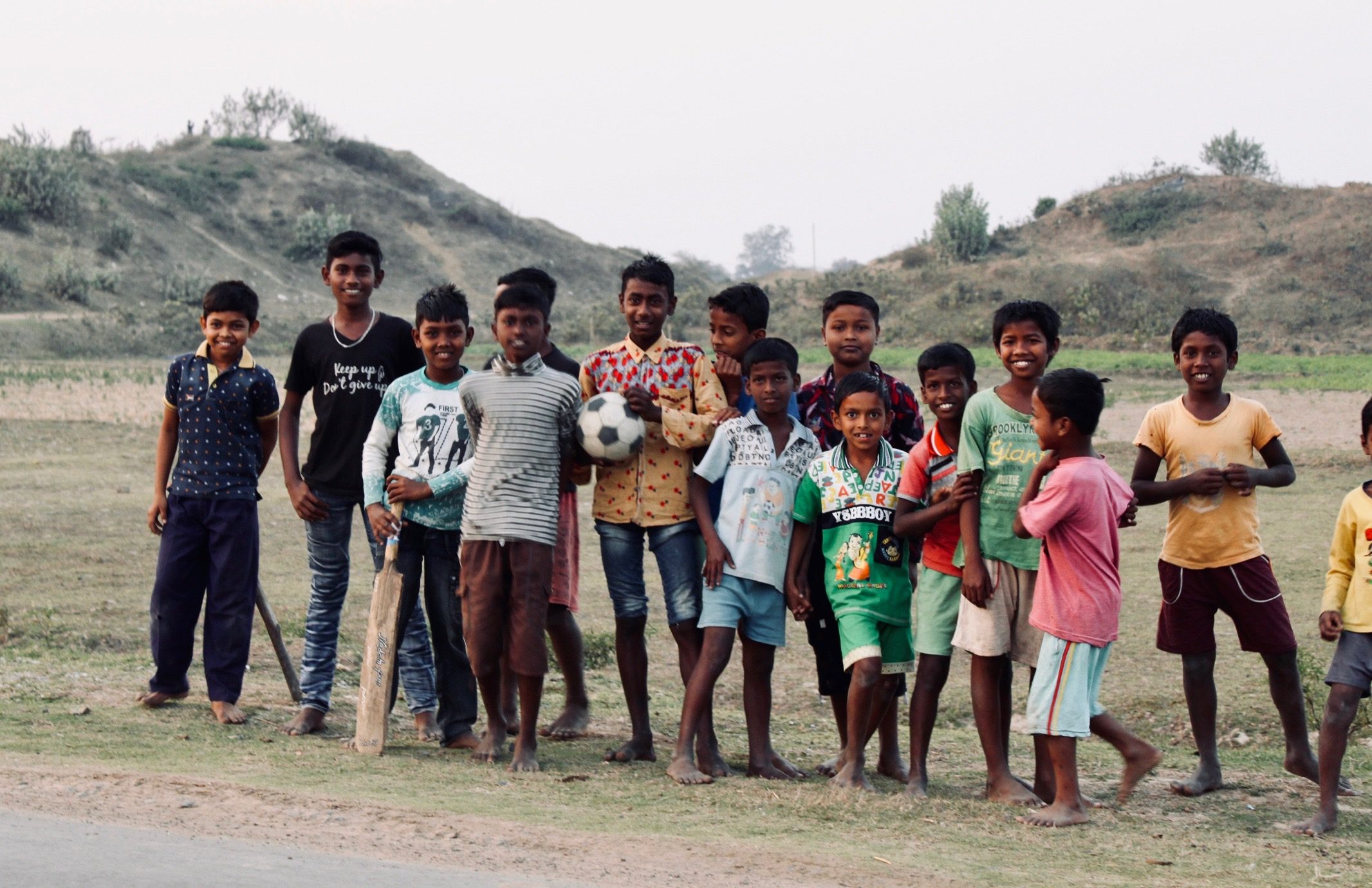 Children in Gurap, India standing together outdoors, one holding a cricket bat and ball