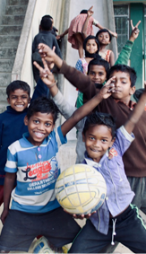 Santal boys smiling and playing with a ball on the school steps