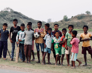 A group of Santal boys with a soccer ball and a cricket bat on a field