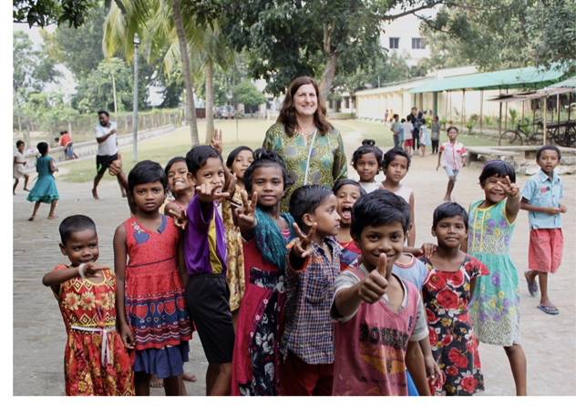 A Tribe Rising India co-founder walking with smiling Santal children on the school grounds