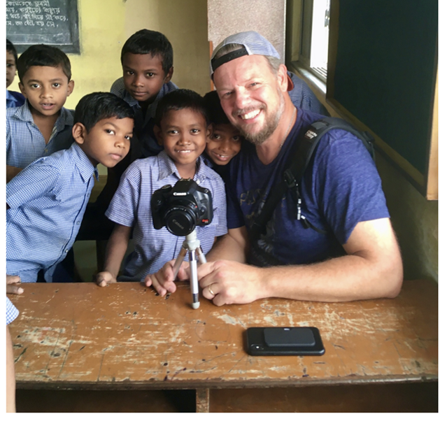 A Tribe Rising India volunteer filming with smiling schoolboys in a classroom