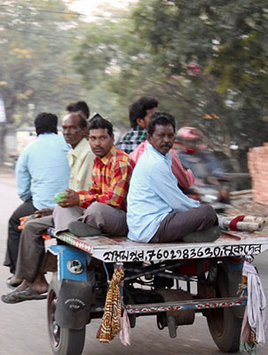 Santal men riding together on a motorized cart in Gurap