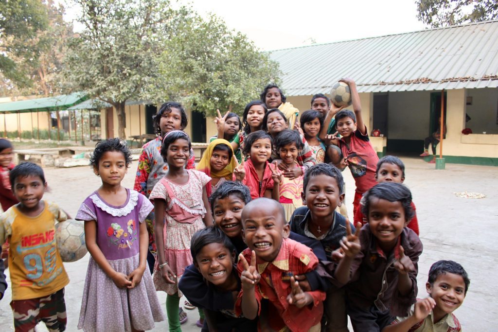 A large group of smiling Santal children playing in the Gurap school yard