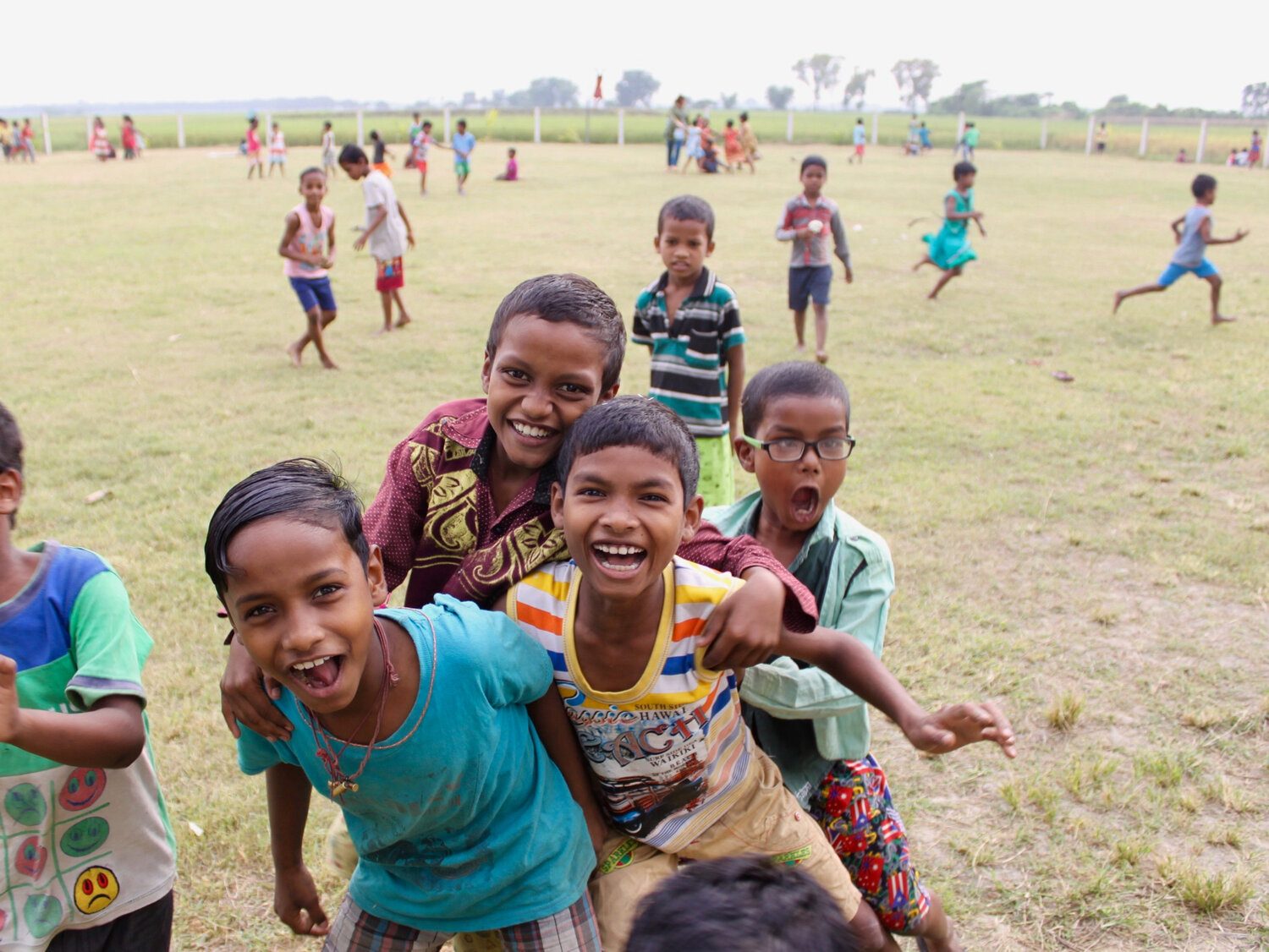 Smiling children running and playing on a grassy field in Gurap, India