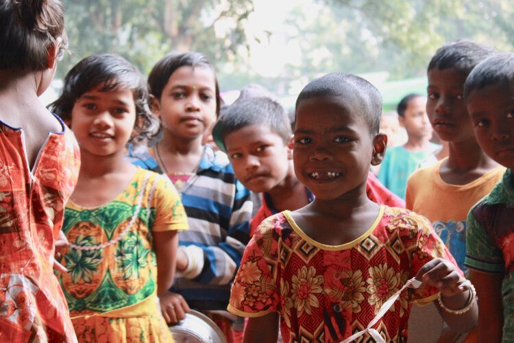 Group of smiling children in colorful clothing outdoors in Gurap, India