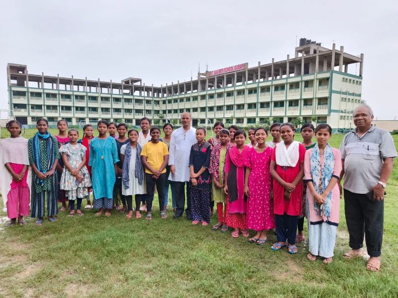 Santal students and staff standing in front of St. Xavier’s School in Gurap, India