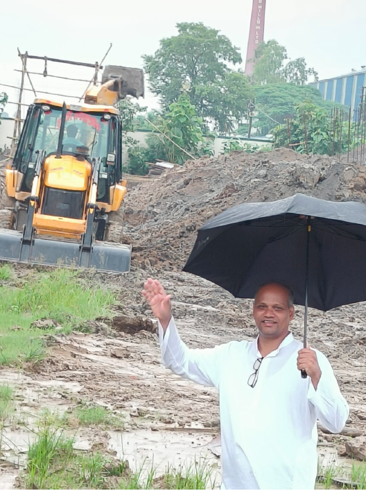 A man at the campus construction site as an excavator digs the ground